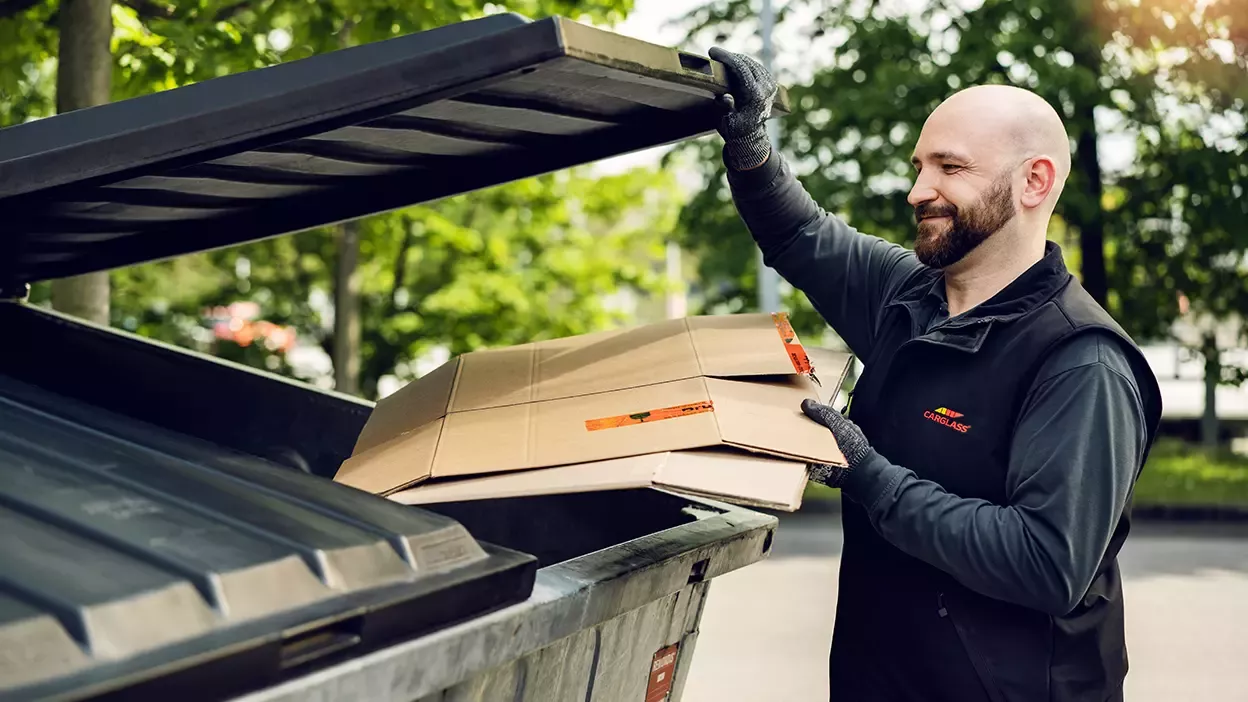 Carglass Mitarbeiter wirft Karton in Papiertonne