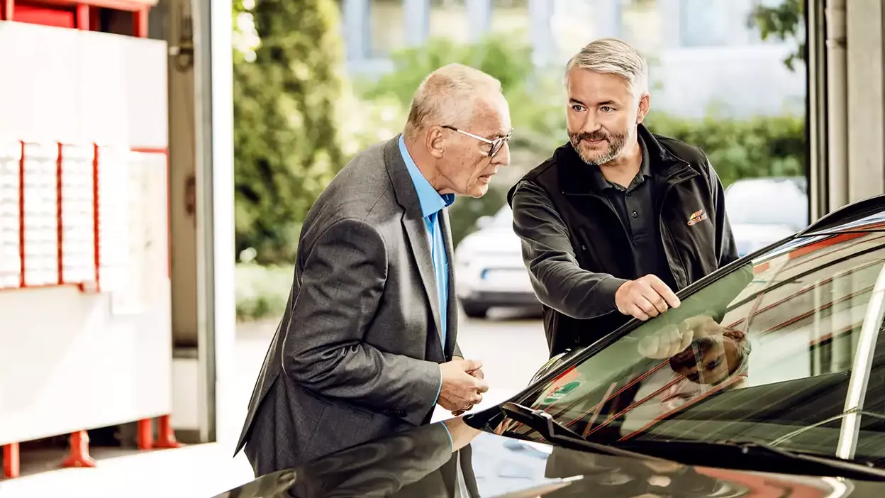 Carglass Monteur begutachtet Windschutzscheibe mit Kunden