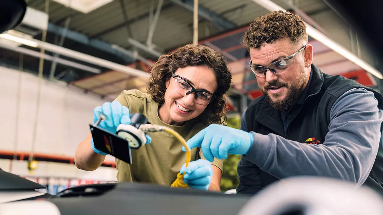 Carglass Mitarbeiter schult neue Kollegin für Reparatur ein